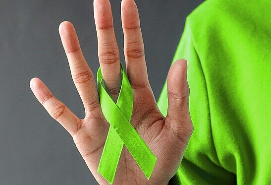 Titelbild Woche der Seelischen Gesundheit | Eine ausgestrecke Hand mit einer grünen Schleife als Symbol für Seelische Gesundheit