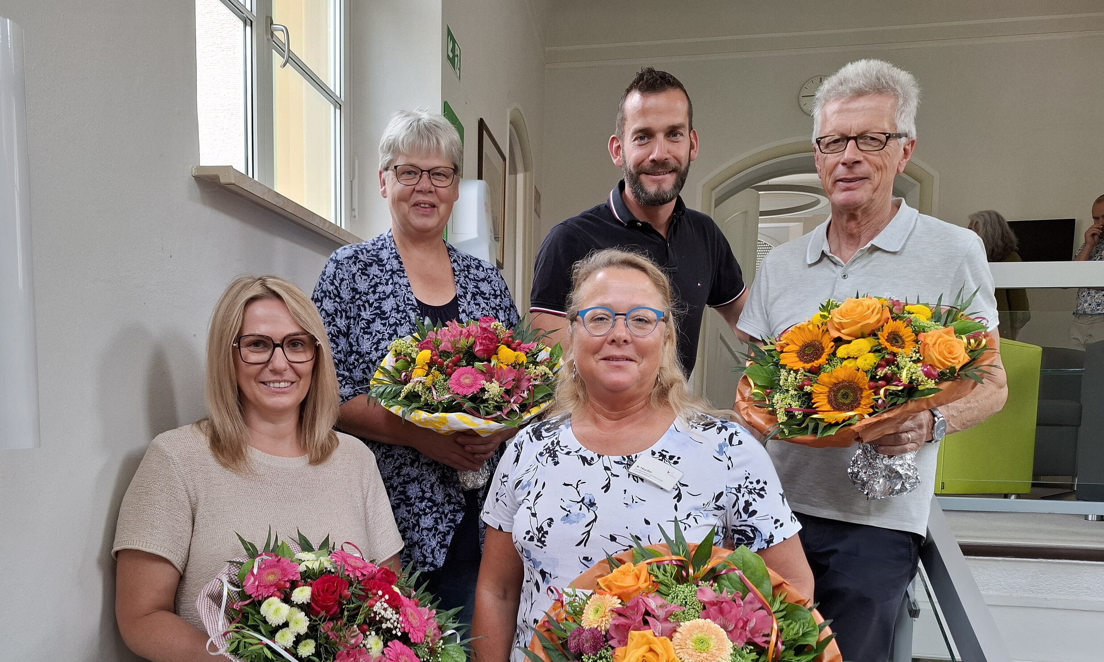 Die Jubilarinnen Michaela Preikschat und Nicole Heyder sowie die frischgebacken Rentner Irmgard Knauer und Gerhard Weiß stehen mit Benjamin Fischer, Kaufmännischer Leiter am Bezirksklinikum Ansbach, nach der Feierstunde auf der Treppe.